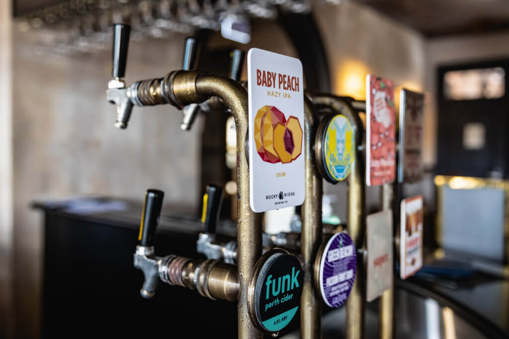Close-up of vintage beer tap handles with colourful craft beer and cider labels including Baby Peach and Funk Perth Cider.