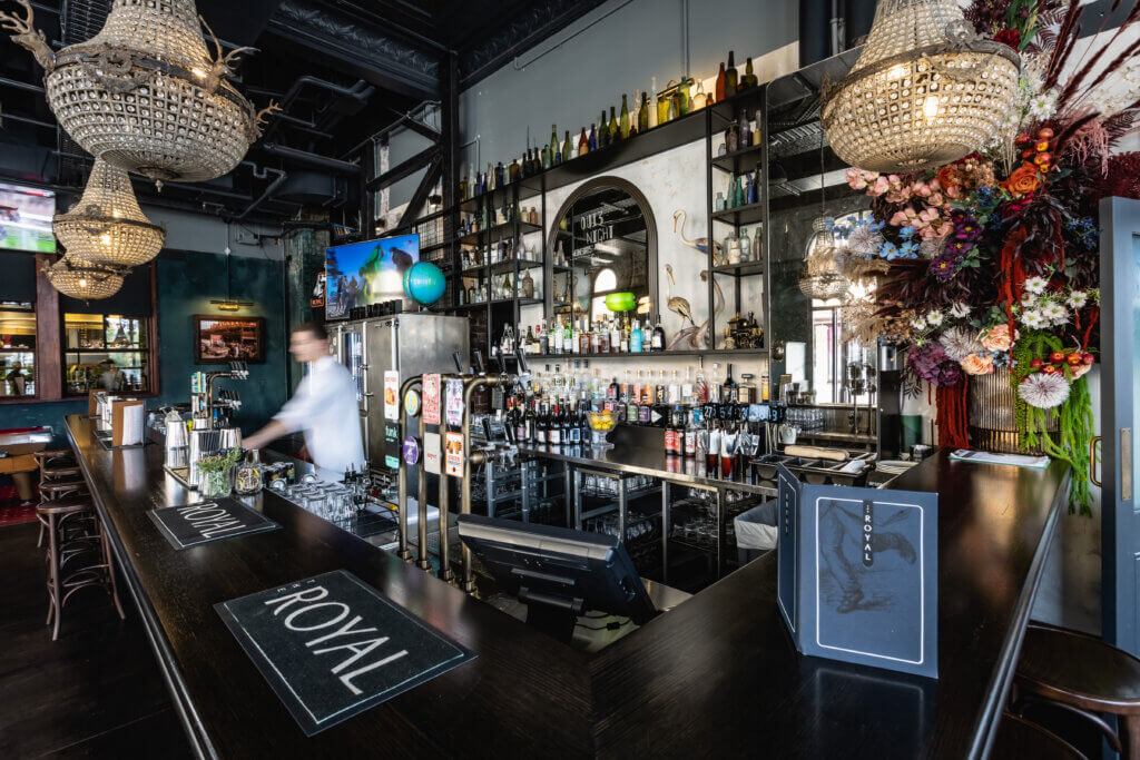 Elegant bar interior with chandeliers, floral display, beer taps and extensive spirits collection at The Royal.