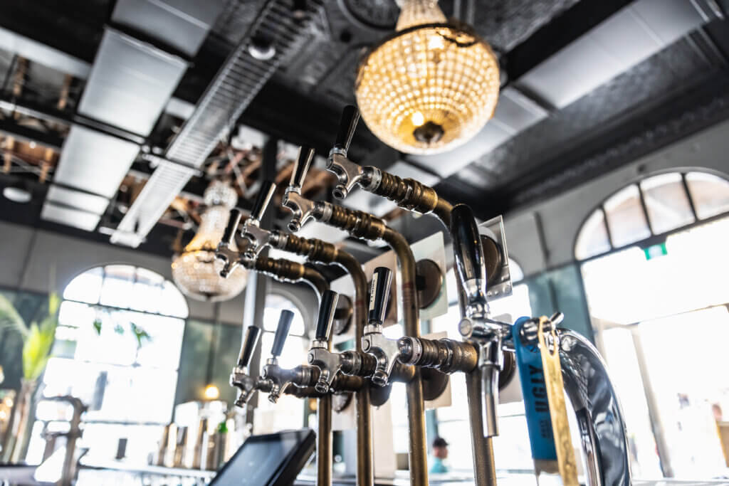 Multiple beer taps installed at a stylish bar, showcasing professional beverage system fitout under chandeliers.