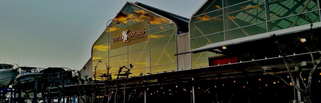 Exterior of Little Creatures Brewing building at sunset, with glass facade reflecting colourful sky.