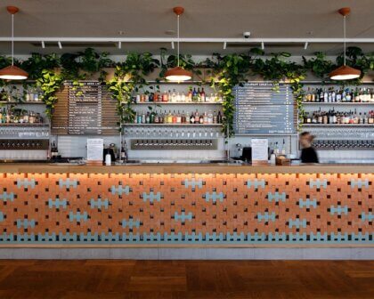 Modern bar at Good Company venue with colourful tiled counter, hanging plants and extensive drinks display.