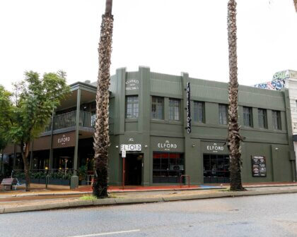 Exterior of The Elford bar in historic Clarke’s 1934 Buildings, surrounded by palm trees.