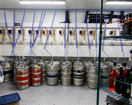 Beer kegs connected to tap system with cooling lines and pumps in a commercial cool room.