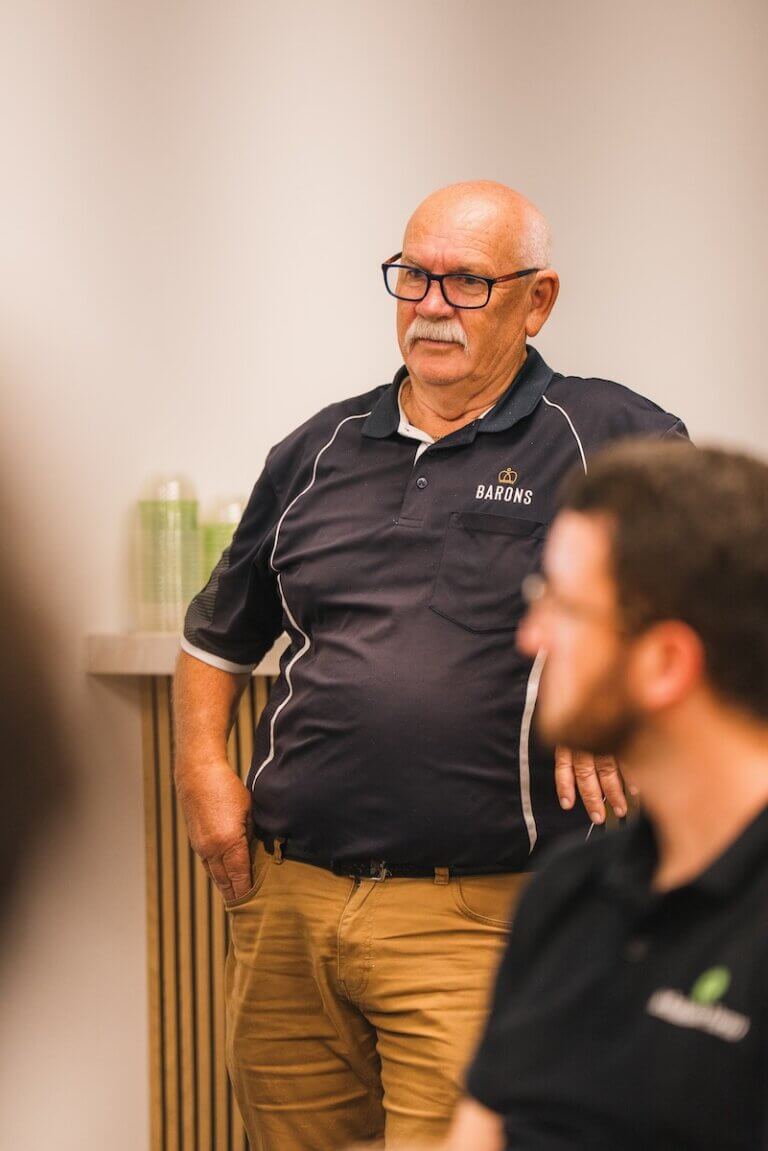A man in Barons polo shirt is listening during a workplace training session.