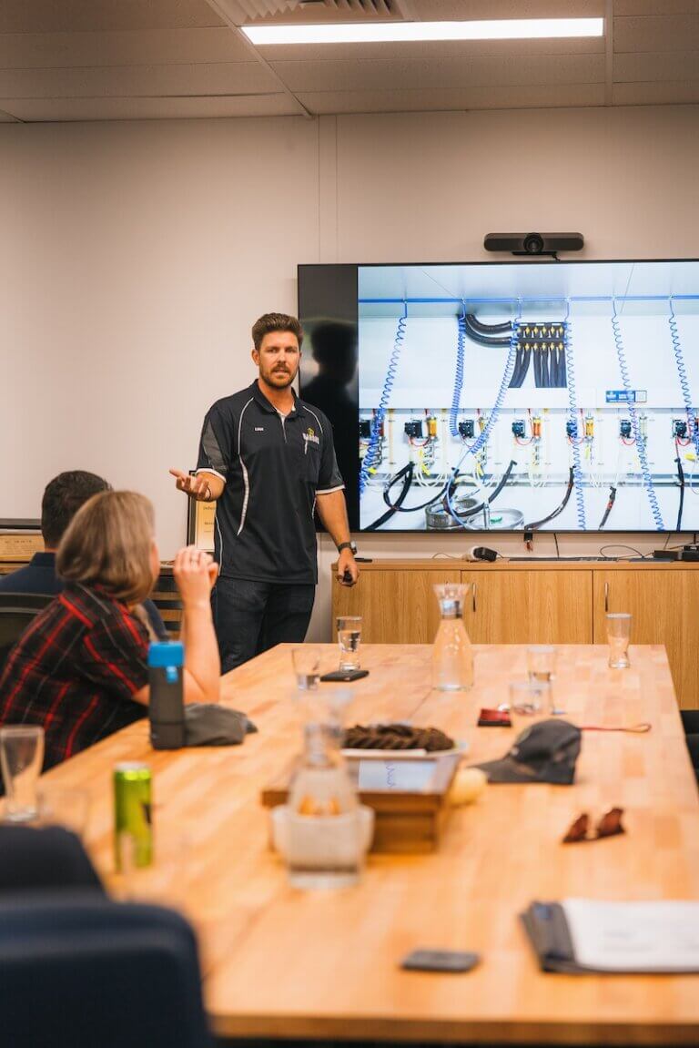 Team training session with a presenter explaining machinery systems on a screen in a modern meeting room.